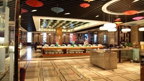A modern hotel lobby with a central reception desk, a seating area, and a decorative ceiling with hanging umbrellas.