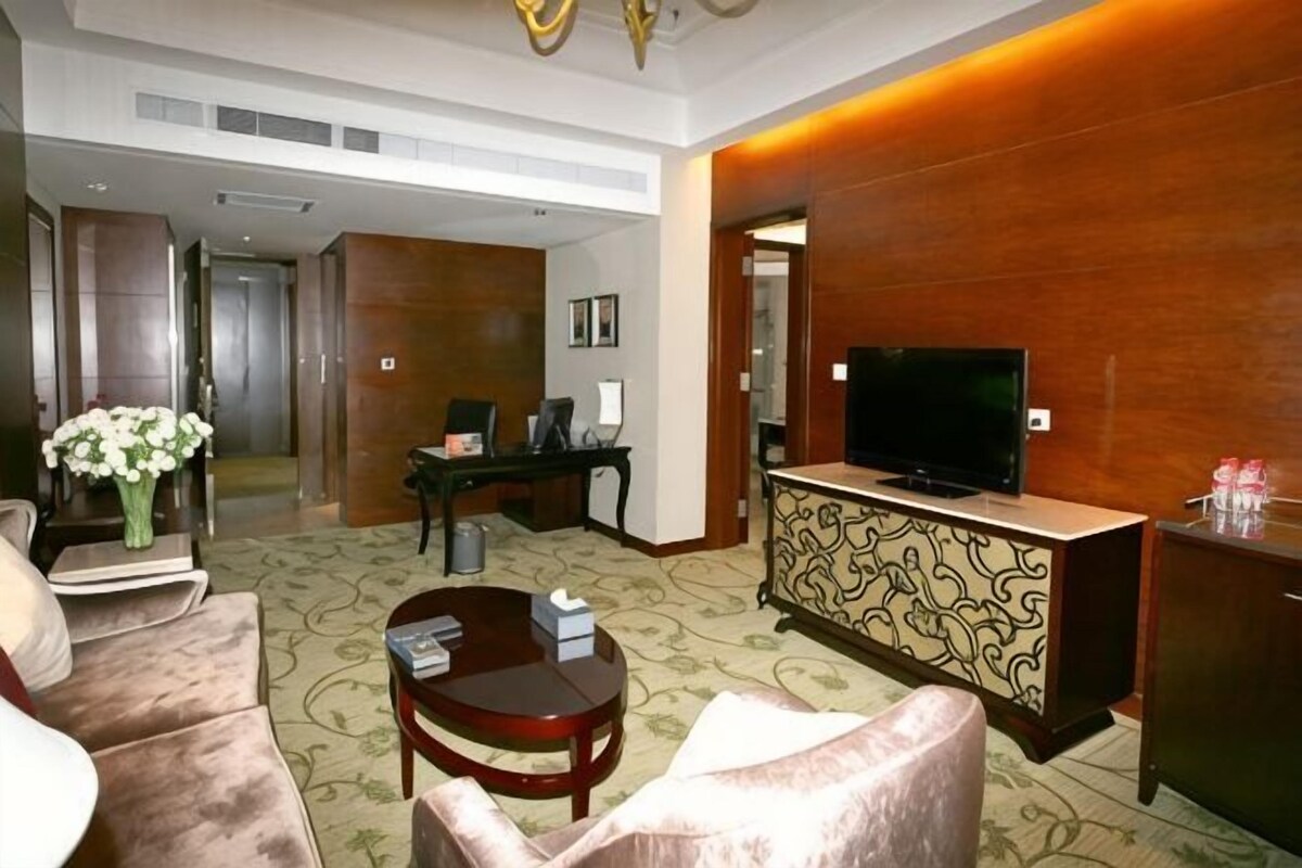 Un hall de hotel con un sofá, una mesa de centro, un escritorio, un televisor y una recepción.