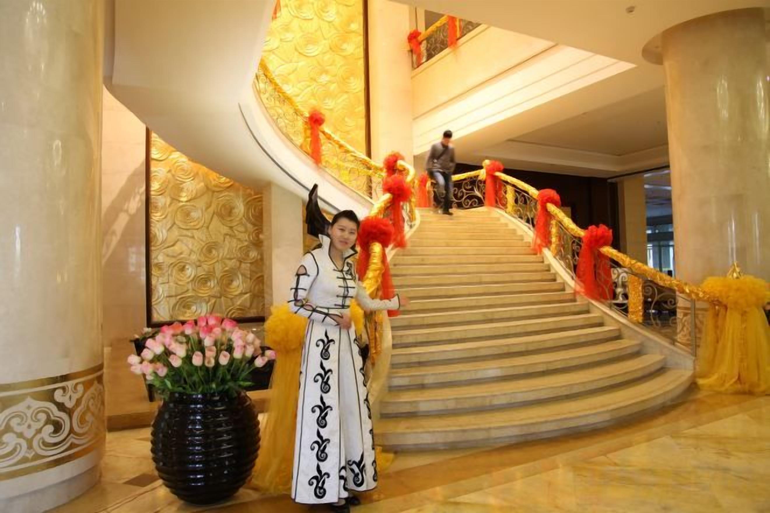 A grand staircase with a curved design, a person in traditional attire, and a vase of flowers.