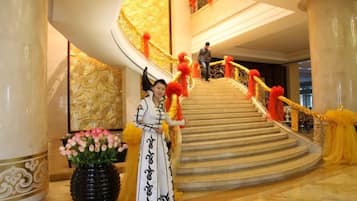 A grand staircase with a curved design, a person in traditional attire, and a vase of flowers.