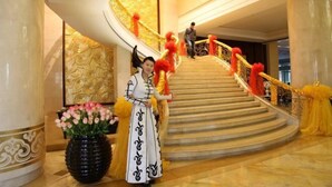 A grand staircase with golden railings and red accents, leading to an upper level.