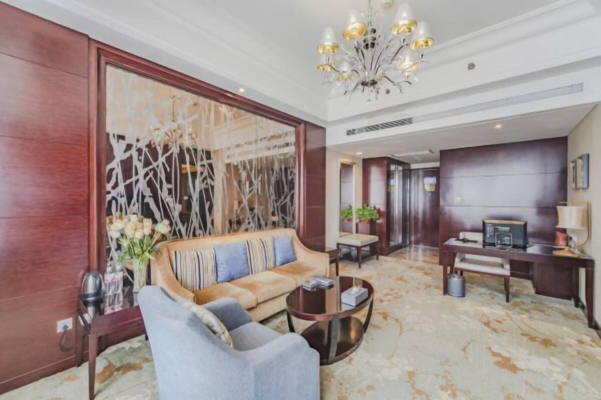 A spacious living area with a sofa, coffee table, and a chandelier.