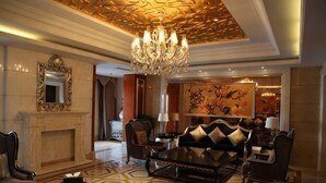 A luxurious living room with a chandelier, a fireplace, a large painting, and a modern sofa set.