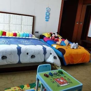 Ein Schlafzimmer mit einem Bett, einem kleinen Tisch mit Spielzeug und einer Wand mit einem Kalender.