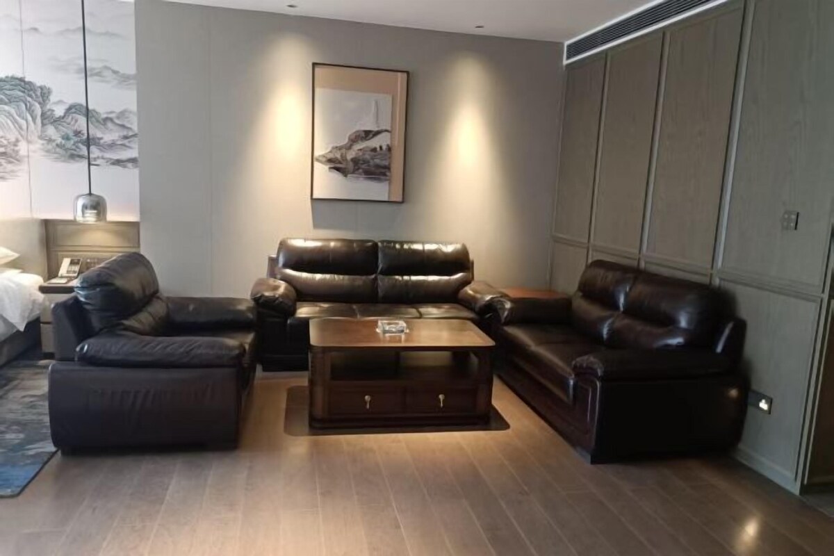 A modern living room with a sectional sofa, a coffee table, and a painting on the wall.