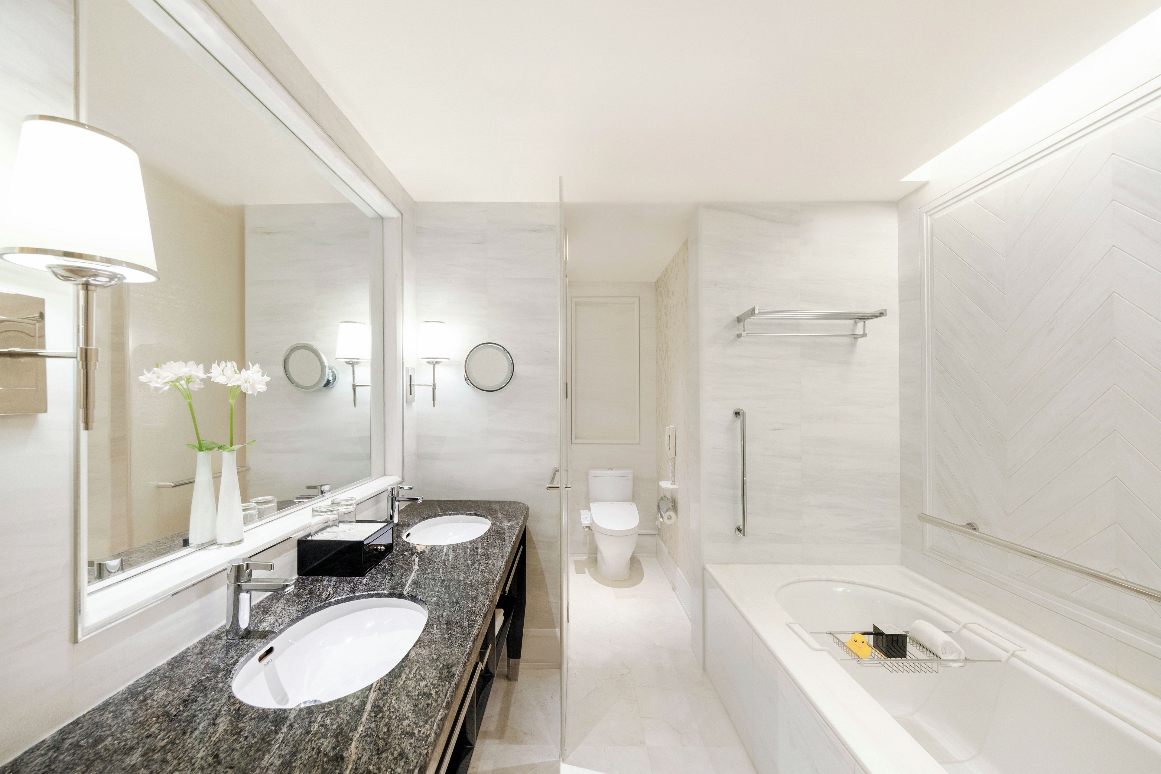 A modern bathroom with two sinks, a toilet, a bathtub, and a shower.