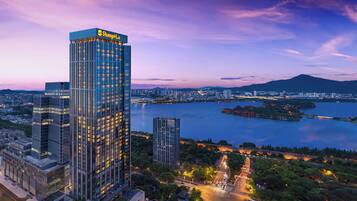 A high-rise building with a prominent sign at the top, surrounded by a cityscape and a body of water.
