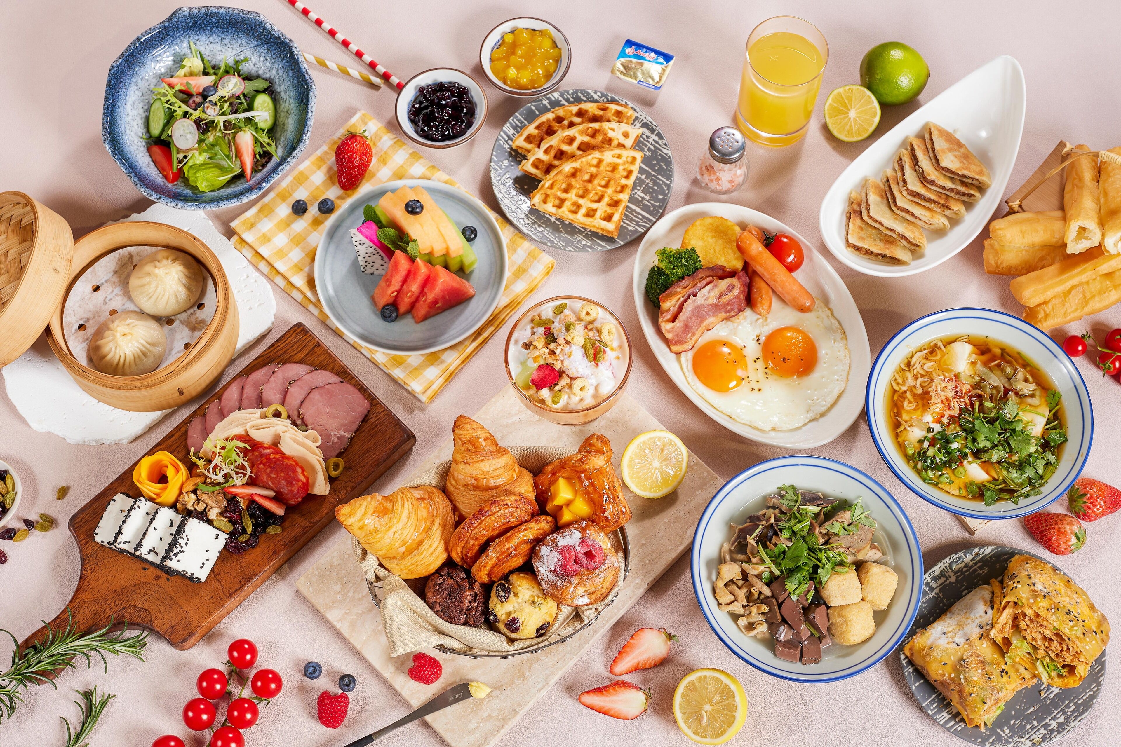 A variety of breakfast foods including waffles, pastries, and a salad.