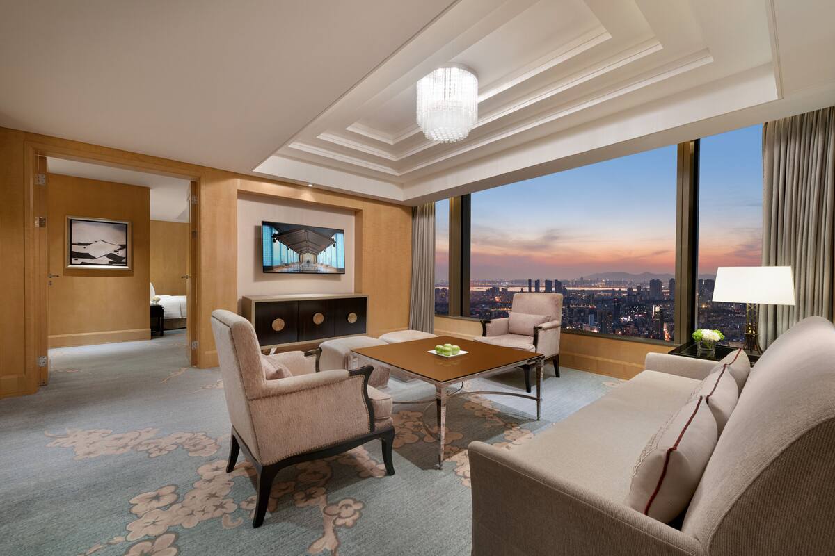 Ein Hotelzimmer mit Blick auf die Stadt, einem Flachbildfernseher, einem Esstisch und einer Couch.