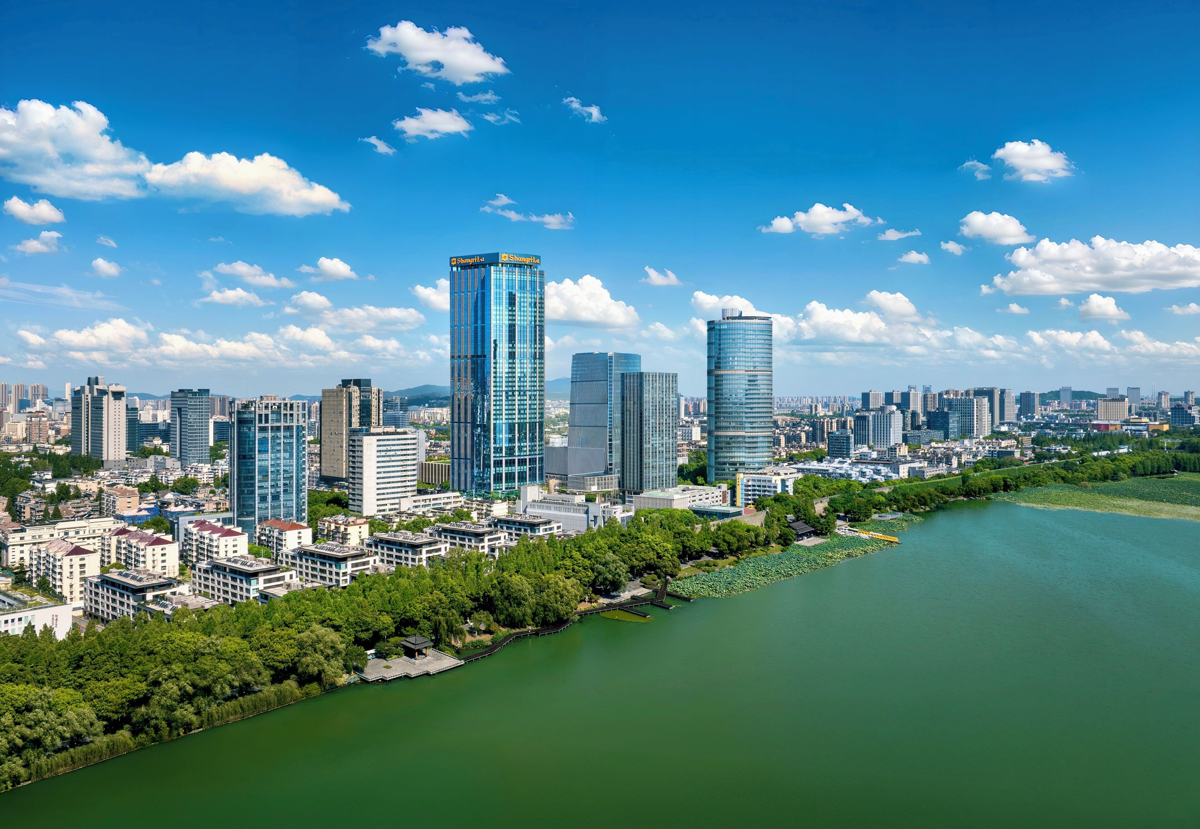 A cityscape with modern skyscrapers, a river, and a park area.