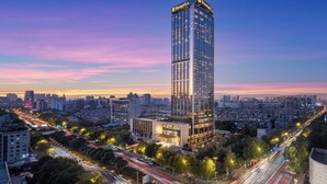 A high-rise building with a modern glass facade, surrounded by a cityscape and busy roads. - Shangri-La Nanjing (Nanjing)