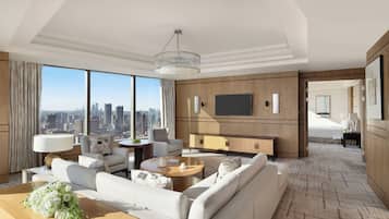 A modern hotel room with a large city view, a sofa set, a dining table, and a TV mounted on the wall.