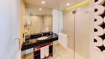 Un baño moderno con cabina de ducha de vidrio, tocador con encimera negra y un espejo grande.