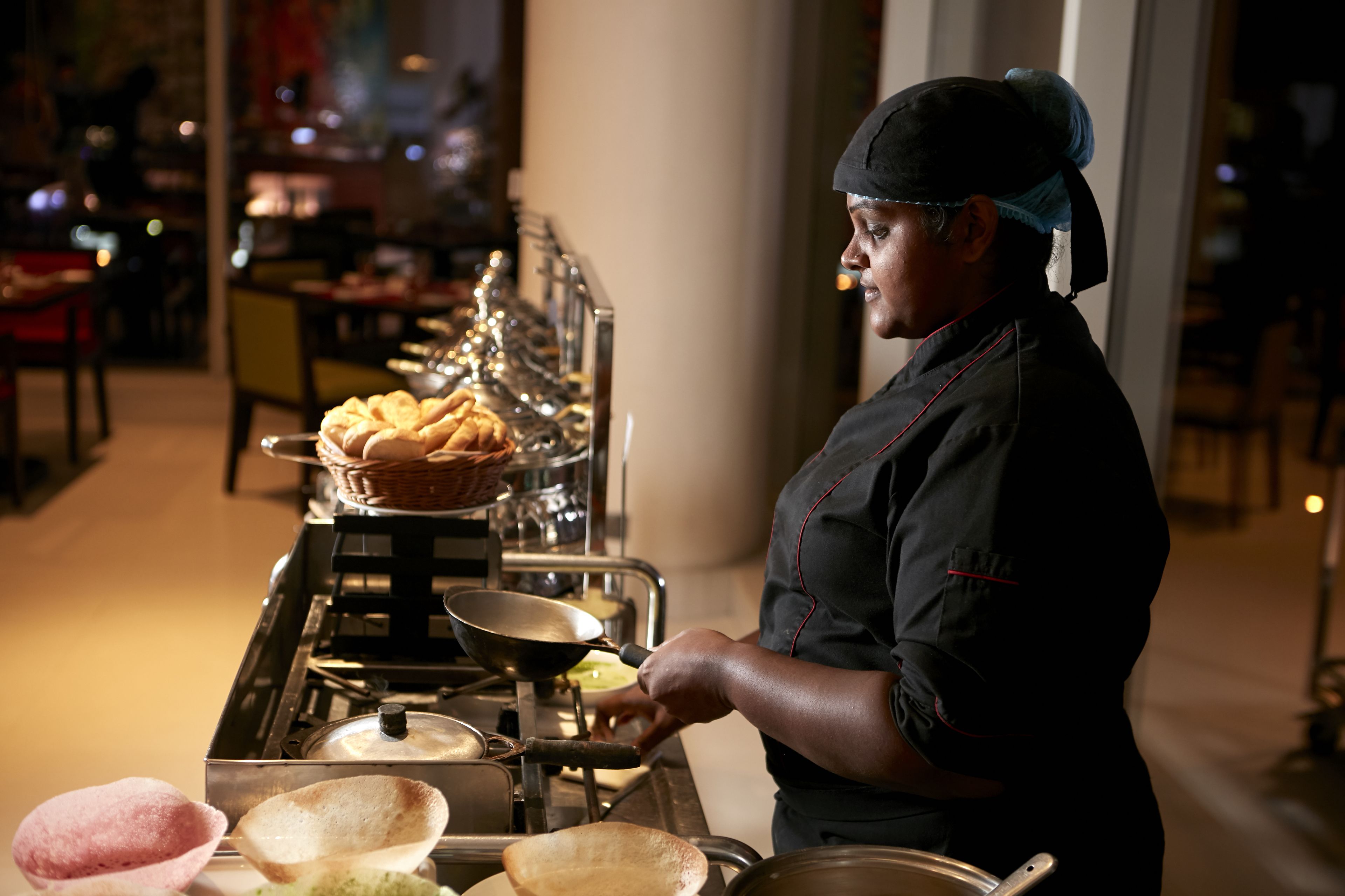 A chef preparing food in a kitchen with a stove, pots, and a variety of dishes.