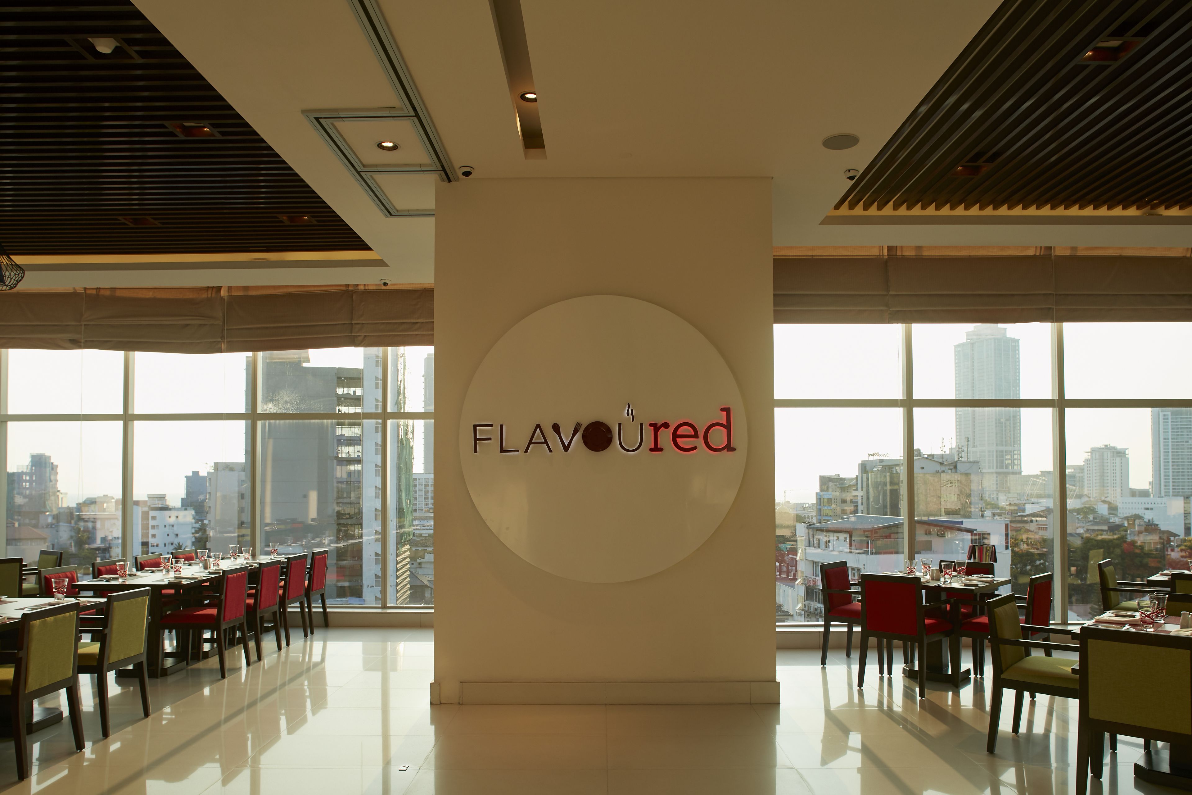 A modern restaurant interior with a large window view of a cityscape.