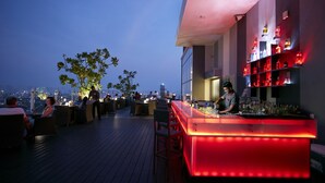 A rooftop bar with a barista preparing drinks, surrounded by tables and chairs, and shelves with bottles. - Cinnamon Red Colombo (Colombo)