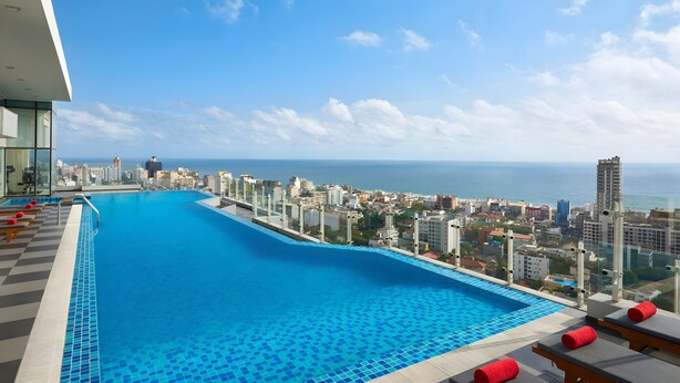 A rooftop infinity pool with a city view, lounge chairs, and a tiled deck. - Cinnamon Red Colombo (Colombo)
