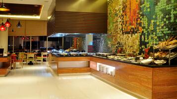A modern hotel lobby with a buffet area, wooden paneling, and hanging pendant lights.