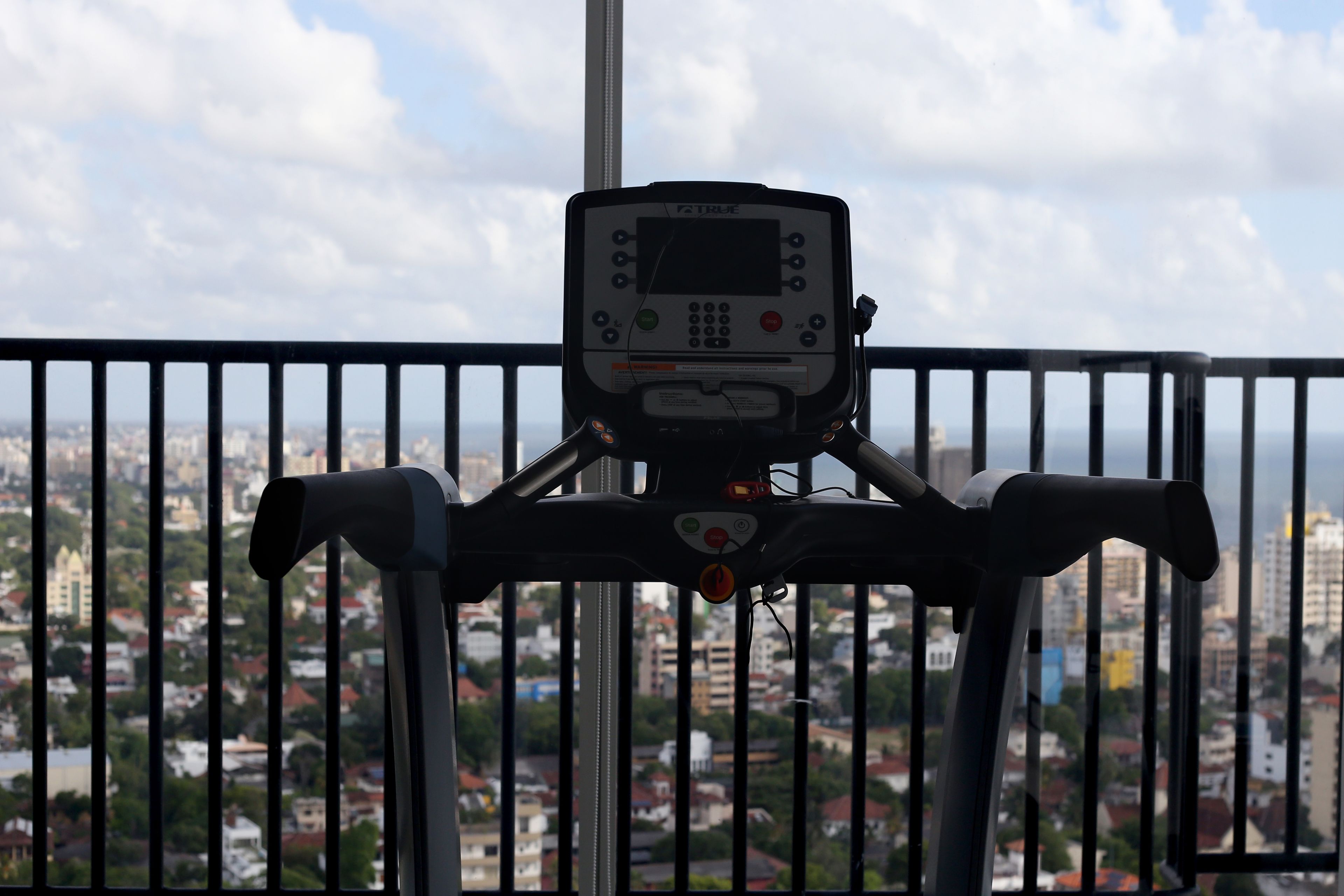 A stationary exercise bike with a digital display, positioned in front of a window overlooking a cityscape.