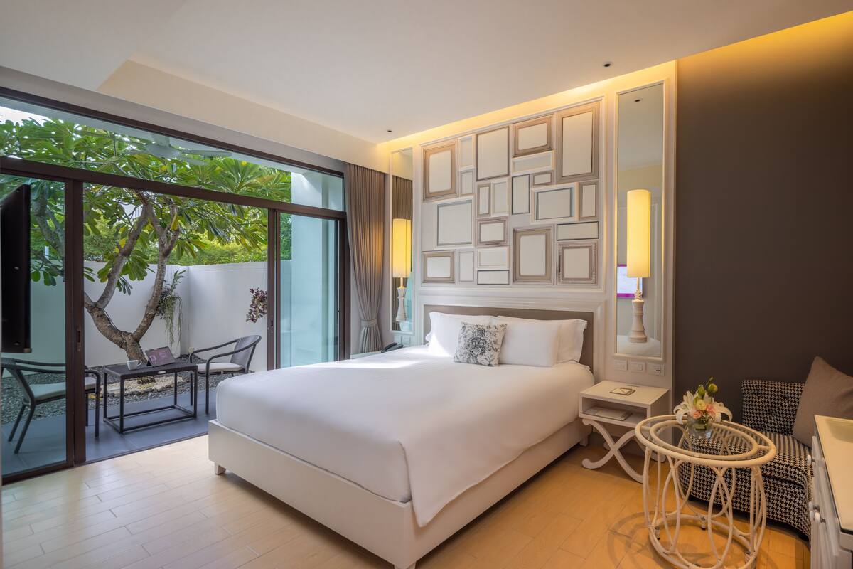 Une chambre d’hôtel moderne avec un grand lit, une petite table, une chaise et une vue sur l’extérieur.