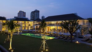 Um hotel com piscina, espreguiçadeiras e palmeiras.