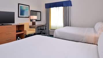 A hotel room with a bed, a desk, a chair, a TV, and a window with curtains.