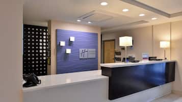 Balcão de recepção de hotel com design moderno, parede azul de destaque e placa indicando Holiday Inn Express.