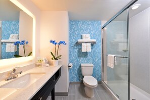 Een moderne badkamer met een glazen douchecabine, een wit toilet en een wastafel met een spiegel erboven.
