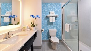 A modern bathroom with a glass shower enclosure, a white toilet, and a sink with a mirror. - Holiday Inn Express & Suites West Ocean City by IHG (Ocean City)