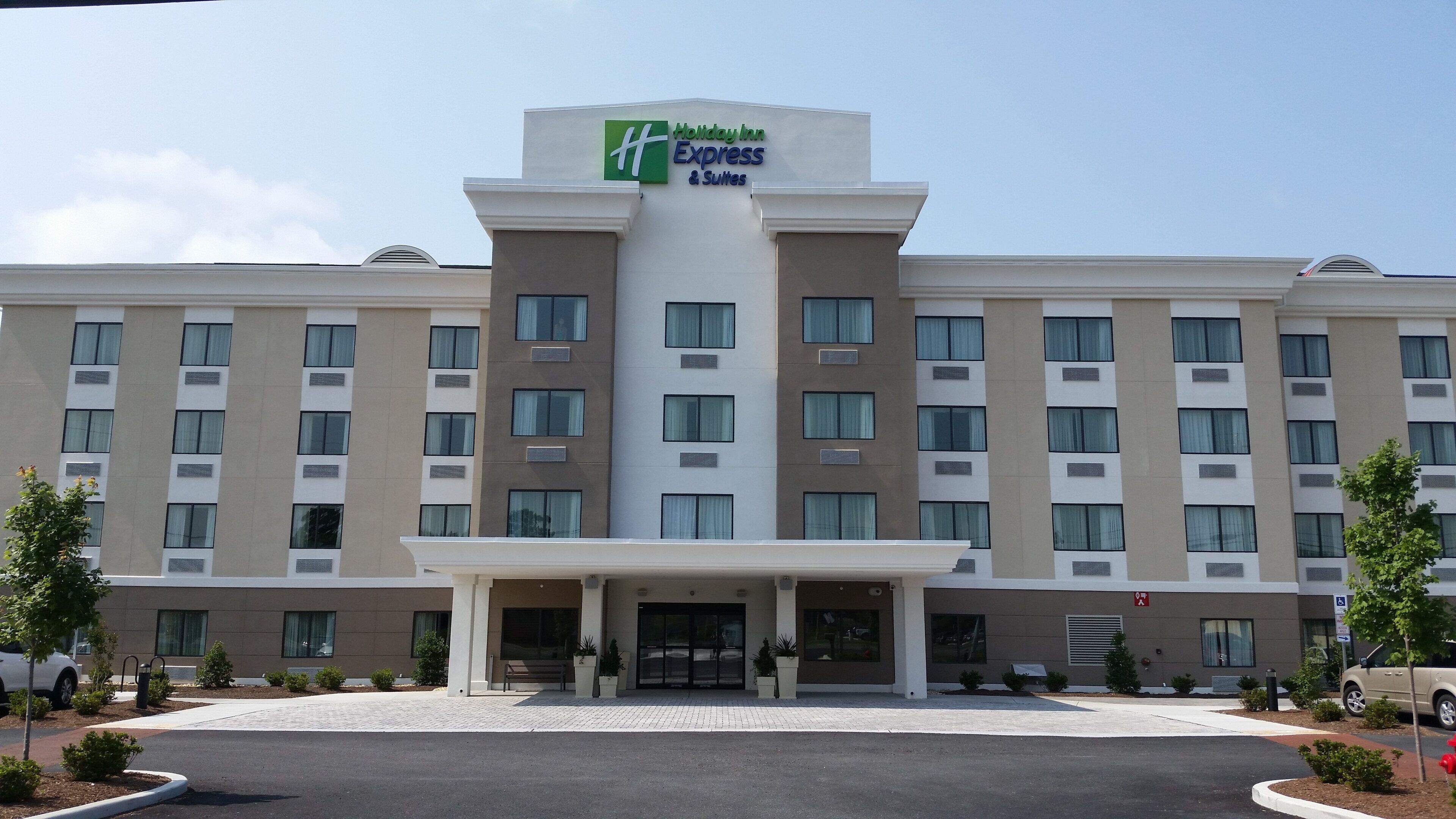 A Holiday Inn Express & Suites hotel with a central entrance, multiple floors, and a parking area.