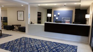 Een hotel receptie met een zwart receptiebalie, een ingelijste kunstwerk aan de muur, en een incheckbalie.