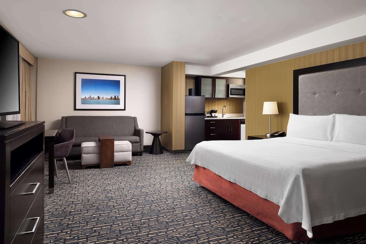 Une chambre d’hôtel comprenant un lit, un canapé, un bureau, une chaise, une télévision et un coin cuisine.