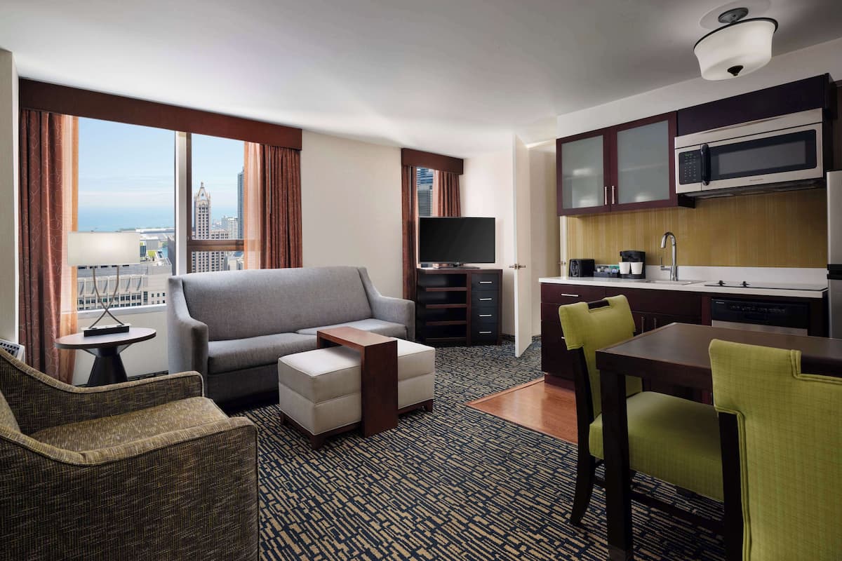 Une chambre d’hôtel équipée d’un canapé, d’un fauteuil, d’une table à manger et d’une kitchenette.