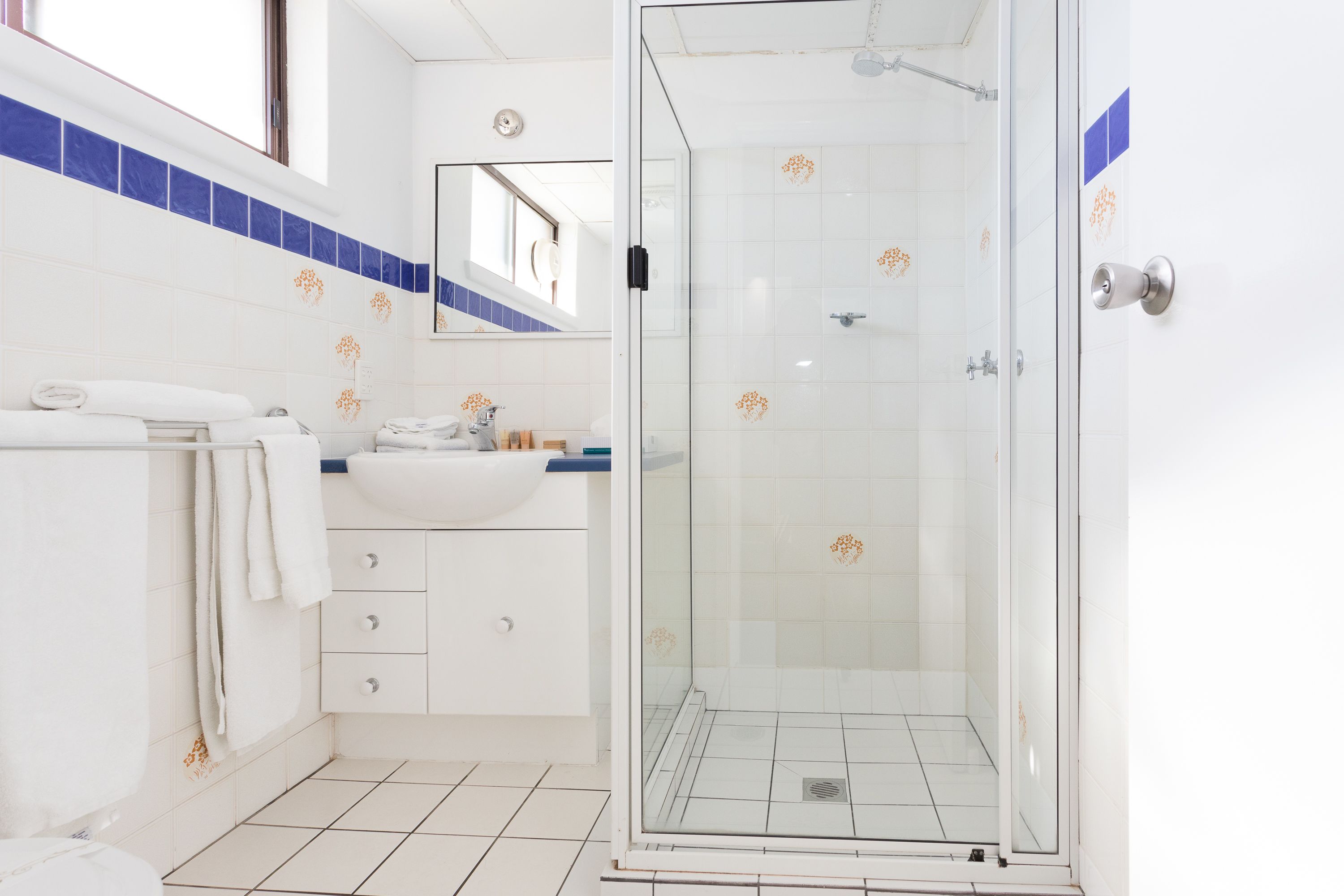 A bathroom with a glass-enclosed shower, a white sink, and a mirror above it.