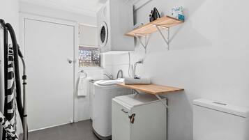 A compact laundry room with a washing machine, a sink, and a toilet.