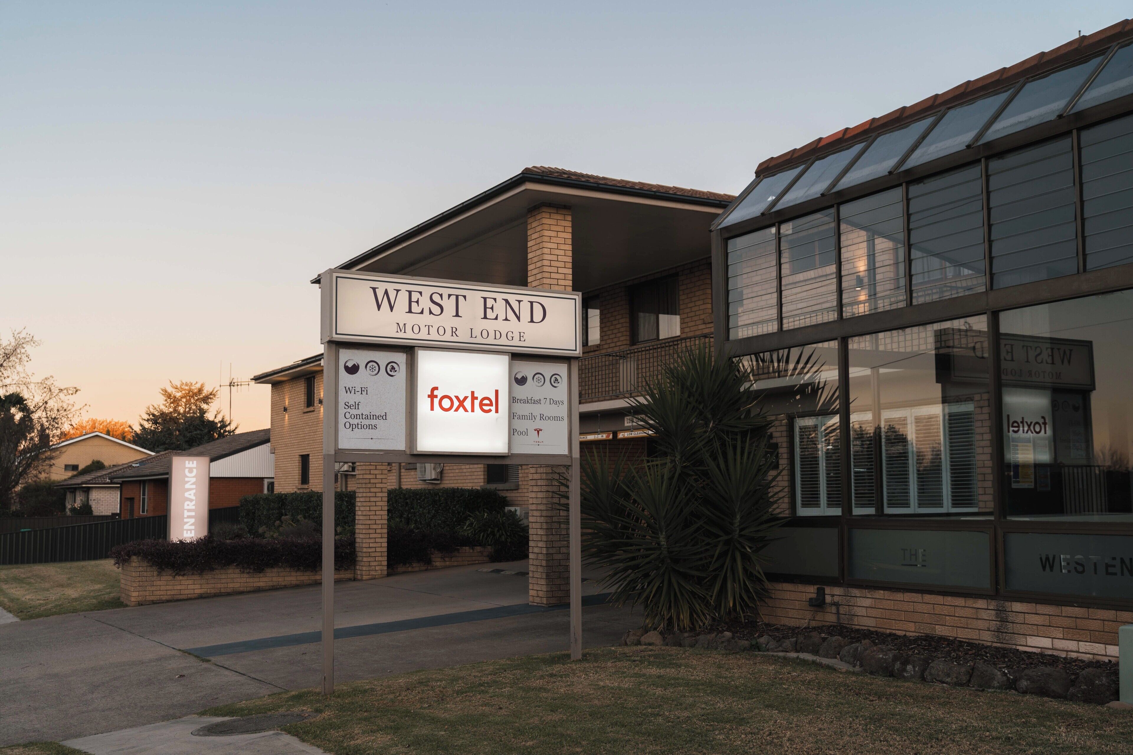 A building labeled "WEST END MOTOR LODGE" with signs indicating Wi-Fi, breakfast for 7 days, family rooms, and a pool.