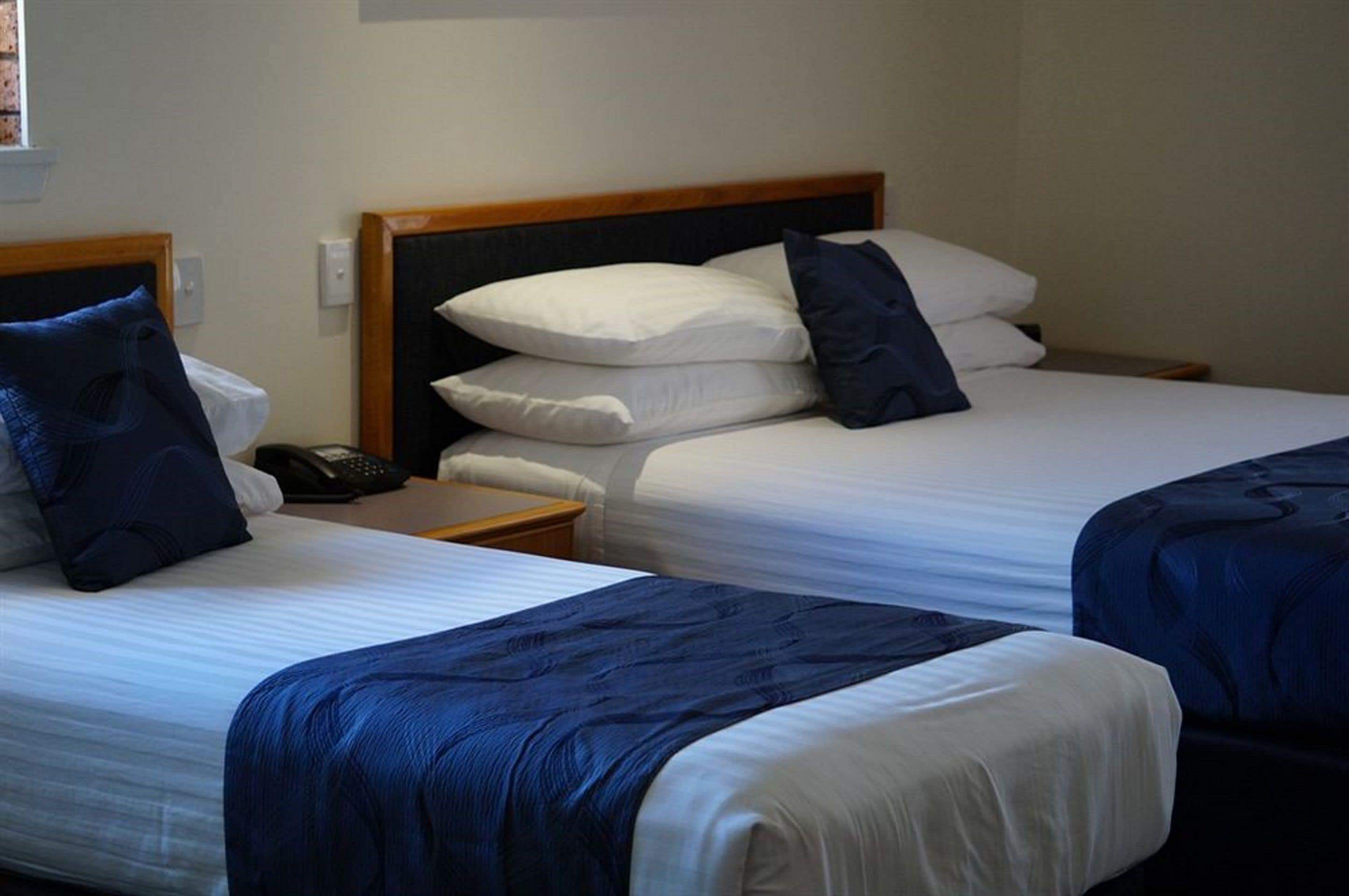Two single beds with wooden headboards, white bedding, and blue throw blankets.