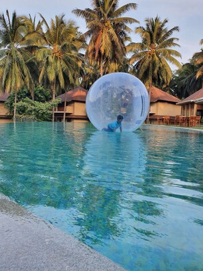 Una piscina nítida envoltada de palmeres i una gran esfera transparent.