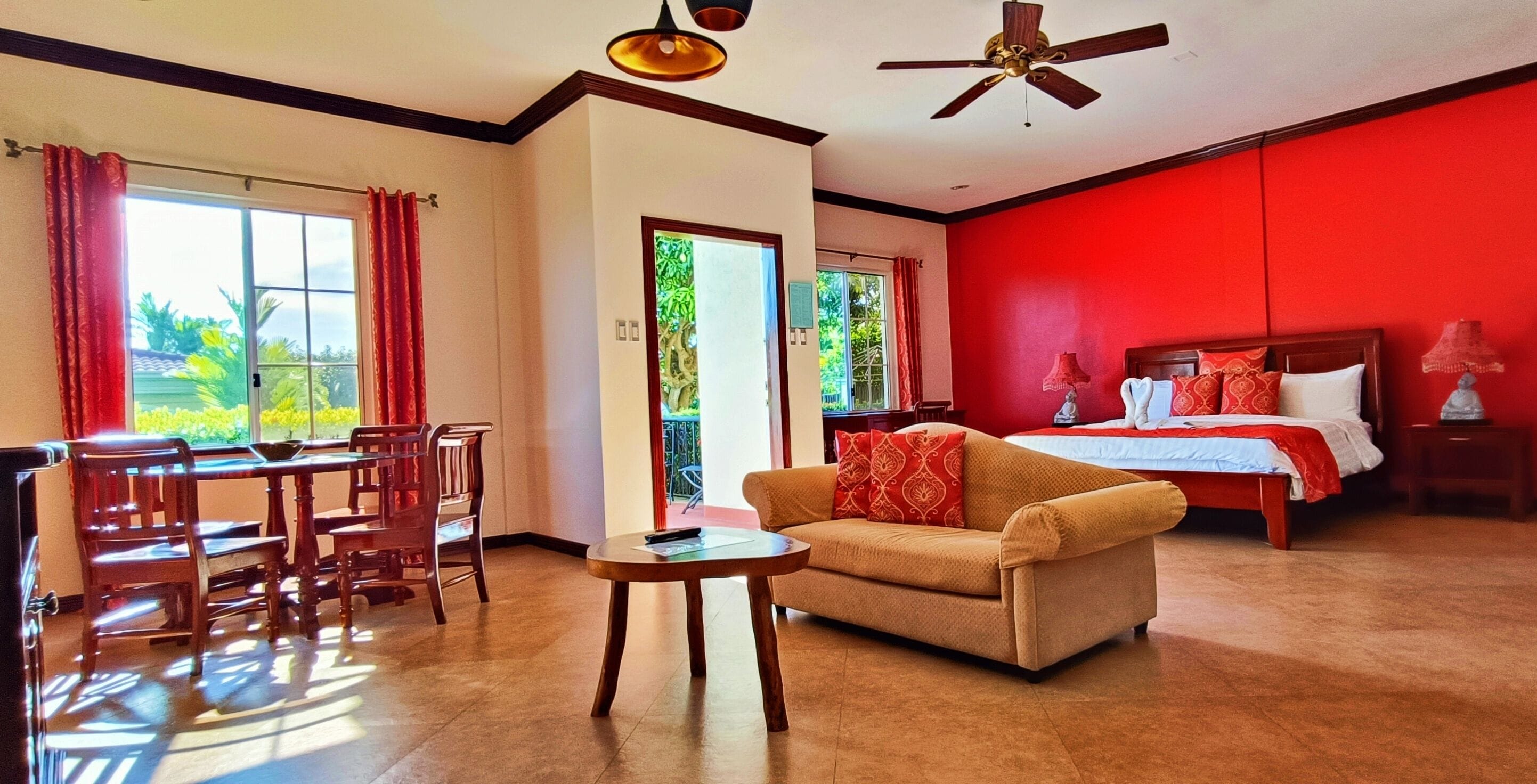 A hotel room with a dining area, a sofa, a bed, and a ceiling fan.