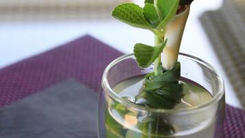 Un cocktail guarnito con una fetta di lime e menta in un bicchiere trasparente.