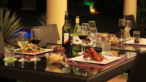 Una mesa de comedor dispuesta con platos de comida, copas de vino y botellas.