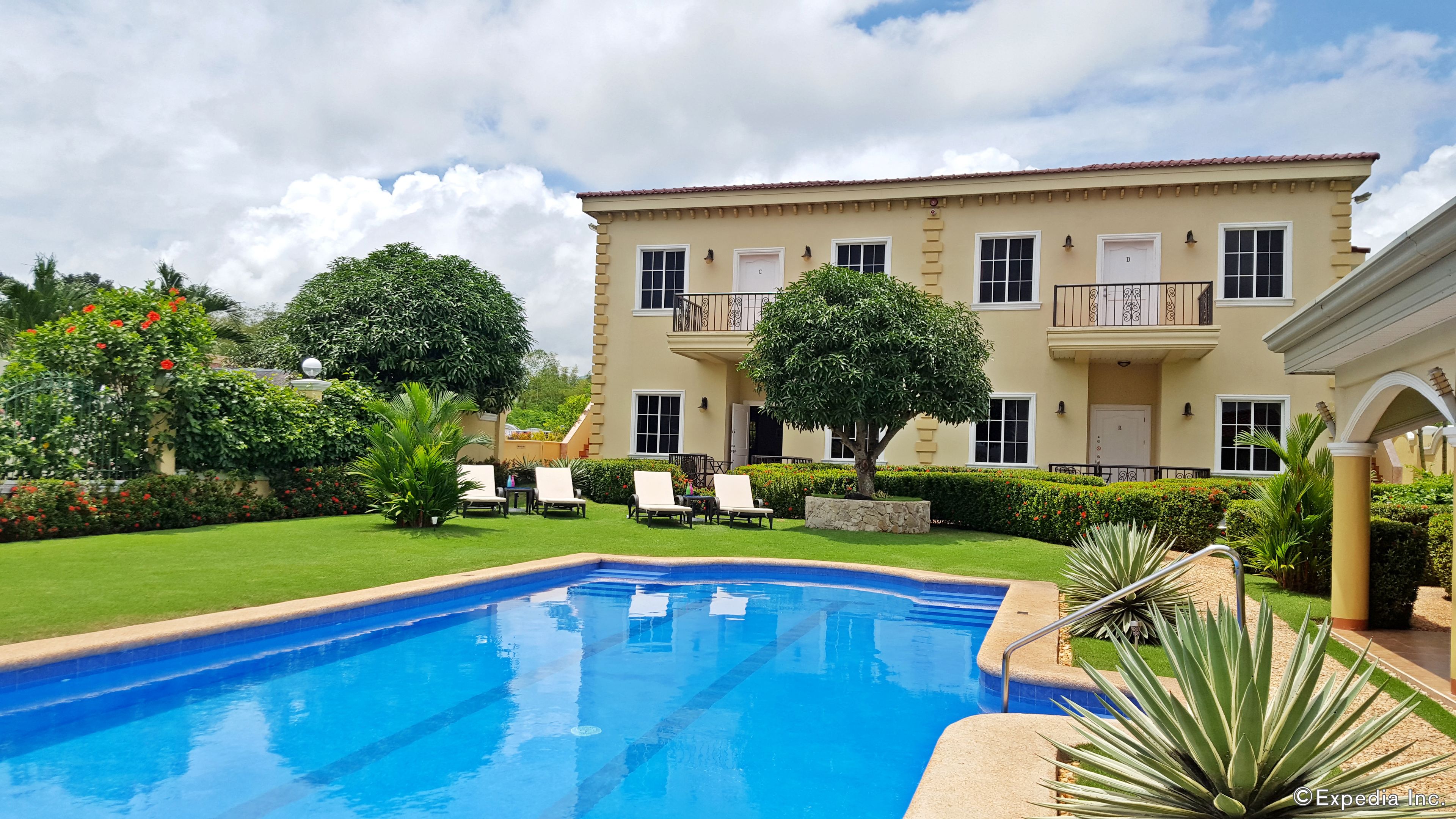 A pool with a clear blue water surface, surrounded by a well-maintained lawn and a large building with multiple windows and balconies.