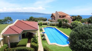 Propiedad residencial con piscina, techo de tejas rojas y vista al mar.