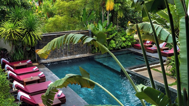 Un área junto a la piscina con sillones de descanso y una cascada.