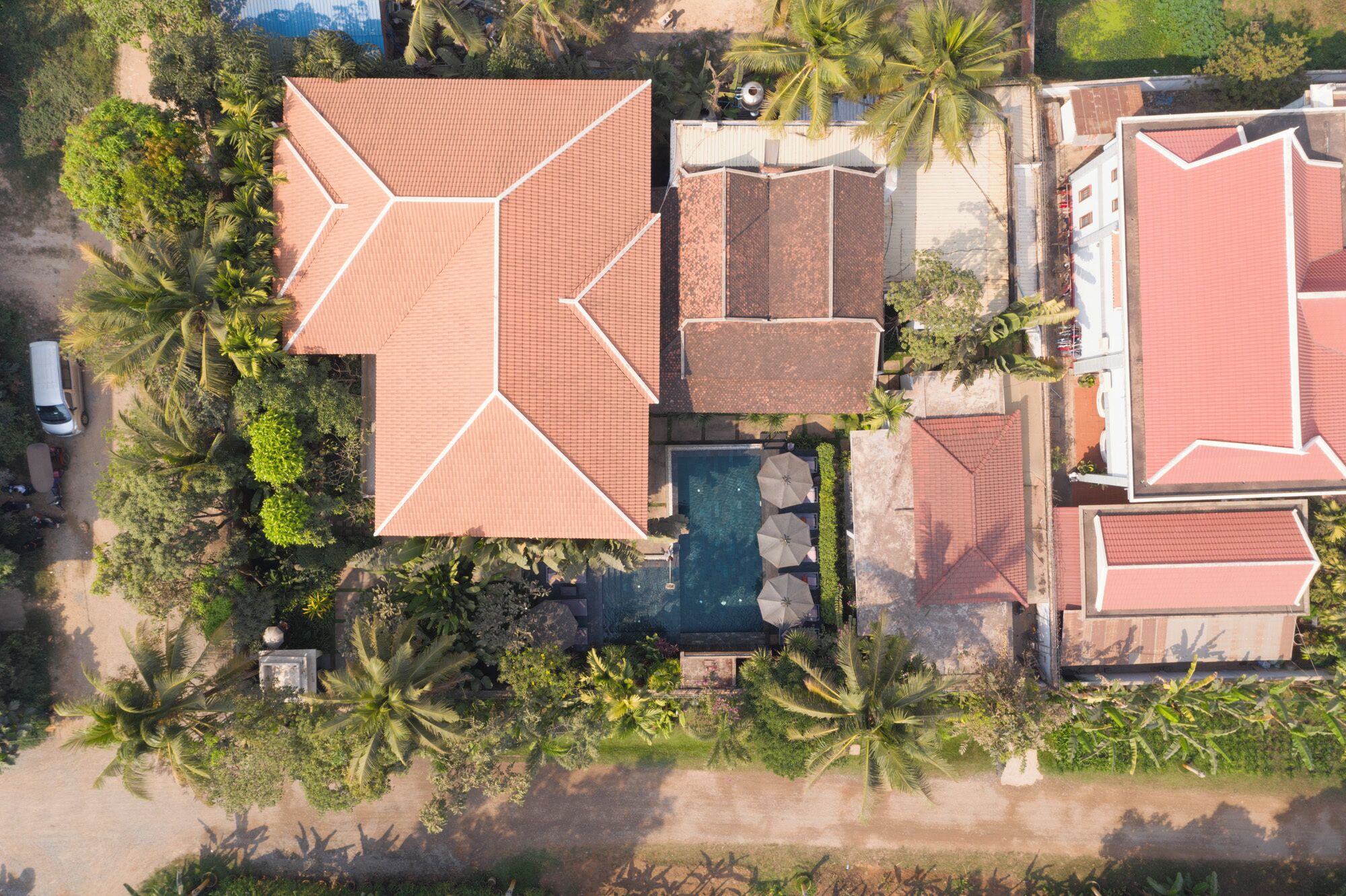 An aerial view of a resort with multiple buildings, a swimming pool, and lush greenery.