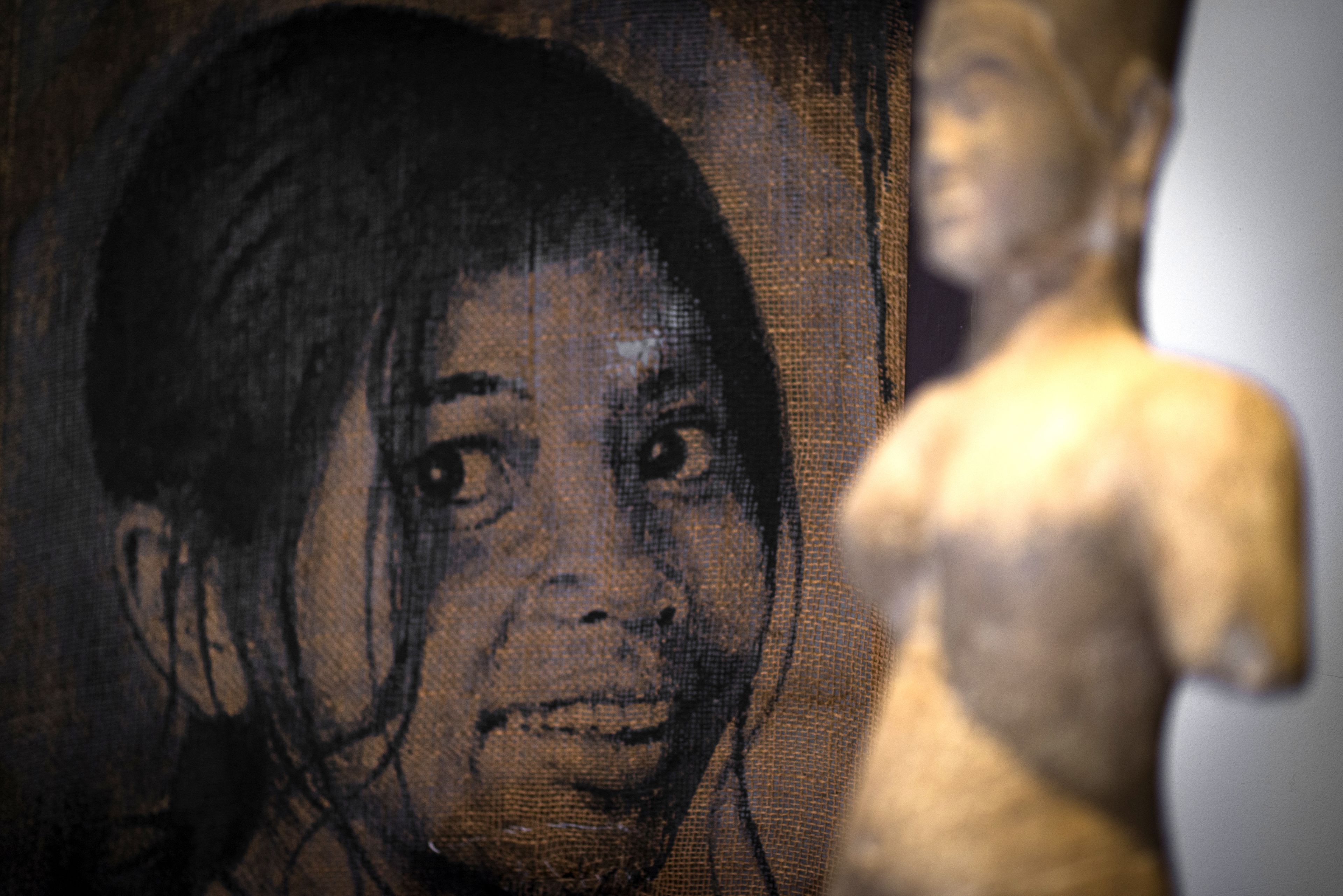 Primer plano de una superficie con textura, una figura borrosa y una escultura.