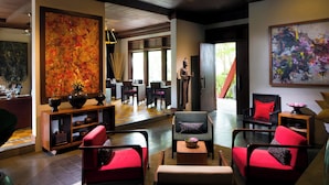 Una sala moderna con sofás rojos, una mesa consola de madera y pinturas abstractas.