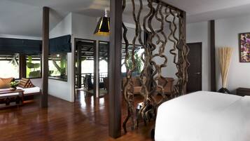 A modern bedroom with a large bed, wooden flooring, a decorative wooden partition, and a view of the outdoors.