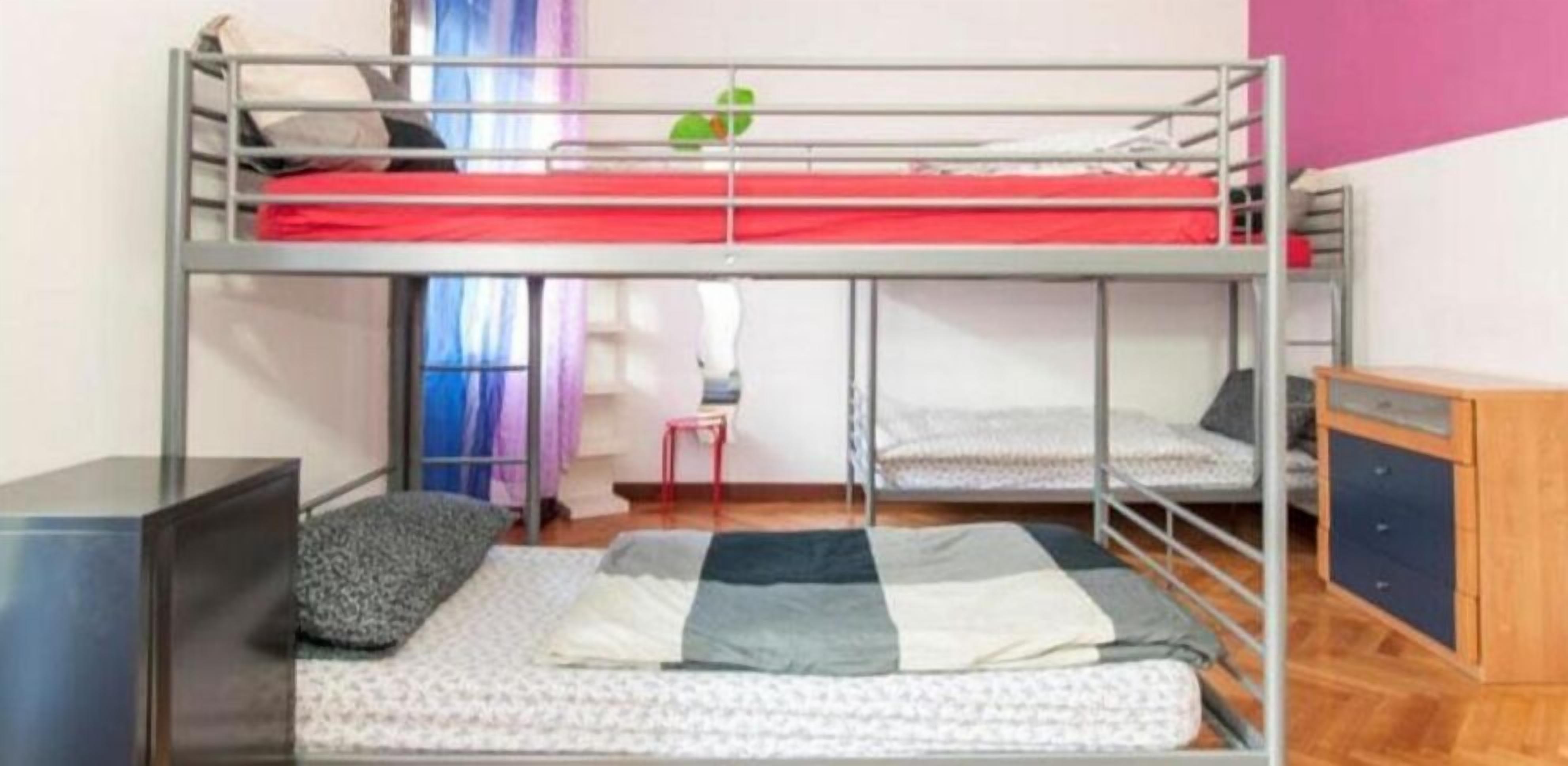 A bunk bed room with a desk and chair, a small table, and a cabinet.