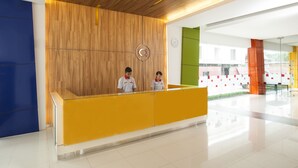 Un mostrador de recepción con dos empleados, una pared de madera y un panel de vidrio.